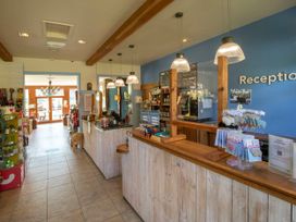 A reception area with a wooden counter and hanging lights at Ardgartan Argyll Silver Birch in Ardgartan Loch Long