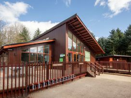 A wooden building with cycle parking racks outside surrounded by trees at Delamere Forest Golden Oak Hideaway in Delamere Forest