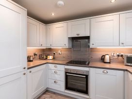 A kitchen with white cabinets a built in oven countertop appliances including a toaster kettle and microwave at Strathyre White Willow Premium in Strathyre Ben Ledi