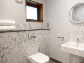 A bathroom with a toilet sink round mirror and window at Strathyre White Willow Premium in Strathyre Ben Ledi