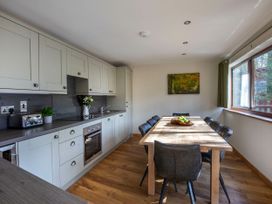 A kitchen with white cabinets a wooden dining table with black chairs and a window at Delamere Forest Golden Oak Treehouse in Delamere Forest