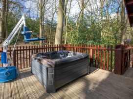 An outdoor deck with a hot tub and a blue seat lift surrounded by wooden railings at Forest of Dean Woodland - Silver Birch wheelchair accessible cabin Forest Of Dean