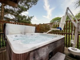 An outdoor hot tub with a seat lift on a wooden deck surrounded by trees at Keldy Classic Silver Birch wheelchair accessible cabin in Keldy Forest