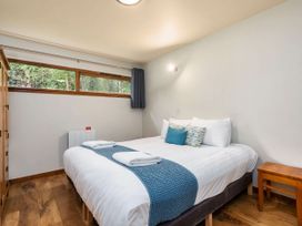 A bedroom with a double bed blue runner towels windows wardrobe and wooden stool at Keldy Classic Silver Birch wheelchair accessible cabin in Keldy Forest