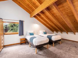A bedroom with two single beds wooden ceiling and a window with blue curtains at Keldy Classic Silver Birch wheelchair accessible cabin in Keldy Forest