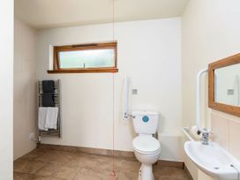 A bathroom with a toilet sink mirror towel rack and a small window at Keldy Classic Silver Birch wheelchair accessible cabin in Keldy Forest