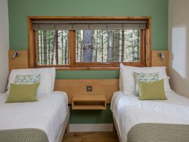 A bedroom with two single beds green and white bedding and a window showing a forest at Sherwood Forest Golden Oak in Sherwood Forest