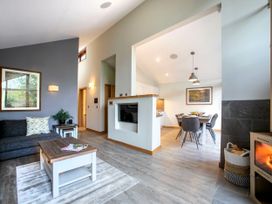 A living room with a sofa a coffee table and a fireplace connected to a dining area with a table and chairs at Delamere Forest White Willow Premium in Delamere Forest
