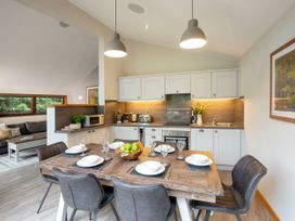 A dining table set with plates and glasses in a kitchen with white cabinets and appliances at Delamere Forest White Willow Premium in Delamere Forest