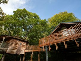 An exterior view of connected wooden treehouses surrounded by trees at Keldy Classic Golden Oak Treehouse in Keldy Forest