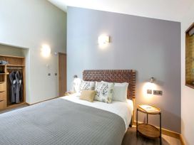 A bedroom with a bed and side table next to wooden shelving with bathrobes in Delamere Forest White Willow Premium Delamere Forest