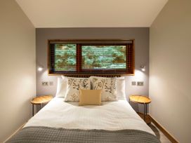 A bedroom with a bed with floral cushions and wooden side tables at Delamere Forest White Willow Premium in Delamere Forest