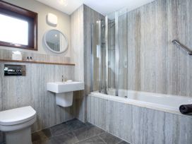 A bathroom with a toilet sink bathtub glass shower screen and wall-mounted mirror at Garwnant Golden Oak in Garwnant Bannau Brycheiniog Brecon Beacons