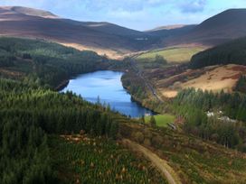 A valley with a lake surrounded by forest and hills with a road running along the side at Garwnant White Willow Premium Valley View in Garwnant Bannau Brycheiniog Brecon Beacons