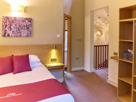 A bedroom with a bed and red pillows next to a wooden shelving unit and a doorway leading to a bathroom at Sherwood Forest Golden Oak in Sherwood Forest