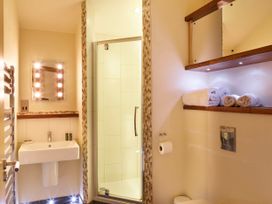 A bathroom with a sink mirror shower and rolled towels on a shelf at Sherwood Forest Golden Oak in Sherwood Forest