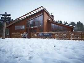 A wooden building with large windows surrounded by snow and a wooden fence at Sherwood Forest Golden Oak in Sherwood Forest