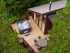 An outdoor wooden deck with a hot tub and a round table with six chairs surrounded by trees at Delamere Forest Golden Oak in Delamere Forest