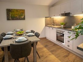 A kitchen with white cabinets a stove and oven a dining table set for six with bowls plates and glasses at Delamere Forest Golden Oak in Delamere Forest