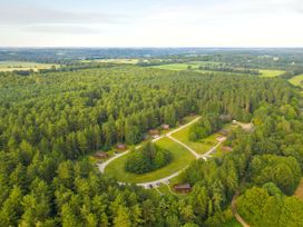 A forest area with wooden cabins and parked cars at Thorpe Forest Golden Oak Treehouse Thorpe Forest