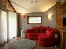 A living room with a red curved sofa a small window and two tree trunk side tables at Beddgelert Golden Oak Hideaway Beddgelert Eryri Snowdonia