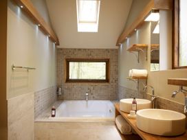 A bathroom with a bathtub under a window and two vessel sinks on a wooden counter at Beddgelert Golden Oak Hideaway in Beddgelert Eryri Snowdonia