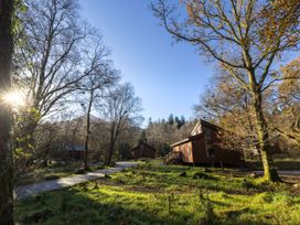 Small wooden cabins among trees and grass near a path on a sunny day at Beddgelert Golden Oak Hideaway Beddgelert Eryri Snowdonia