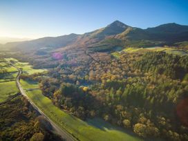 An aerial view of a mountain with surrounding forest and fields along a road at Beddgelert Golden Oak Hideaway Beddgelert Eryri Snowdonia