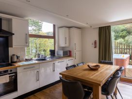 A kitchen with white cabinets and wooden countertops next to a dining table with black chairs and a wooden bowl at Deerpark Classic Silver Birch in Deerpark Forest
