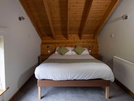 A bedroom with a bed with white bedding and green pillows under a wooden slanted ceiling at Deerpark Classic Silver Birch in Deerpark Forest