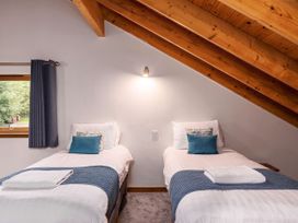 A bedroom with two single beds under a wooden slanted ceiling at Deerpark Classic Silver Birch in Deerpark Forest