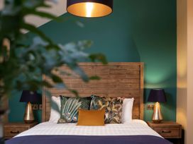 A bedroom with a wooden headboard bed two bedside tables with lamps and decorative pillows at Cropton Golden Oak Hideaway Cropton Forest