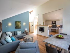 A living room with gray sofas and a wooden coffee table next to a dining table with black chairs and green apples in a bowl at Garwnant Silver Birch wheelchair accessible cabin Garwnant Bannau Brycheiniog Brecon Beacons
