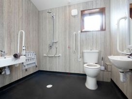A wheelchair accessible bathroom with a shower, toilet, two sinks, grab bars and a window at Garwnant Silver Birch wheelchair accessible cabin in Garwnant Bannau Brycheiniog Brecon Beacons