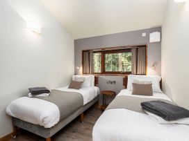 A bedroom with two single beds side by side a window between them and folded towels on each bed at Glentress Forest White Willow Premium Valley View in Glentress Forest Peebles