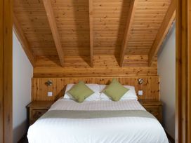 A bedroom with wooden ceiling and walls a bed with white bedding and green pillows at Deerpark Classic Golden Oak Waterside in Deerpark Forest