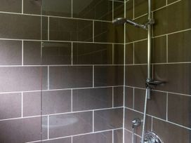 A tiled shower area with a metal showerhead and control at Deerpark Classic Golden Oak Waterside in Deerpark Forest