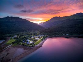 A coastal village with buildings surrounded by forest and mountains at sunset at Ardgartan Argyll Silver Birch in Ardgartan Loch Long