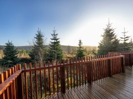 A wooden deck with railing overlooking trees and hills at Garwnant Golden Oak Treehouse in Garwnant Bannau Brycheiniog Brecon Beacons