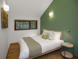 A bedroom with a bed with white and green bedding a wooden floor and a small round side table at Ardgartan Argyll Golden Oak Lochside Ardgartan Loch Long