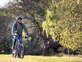 A man wearing a helmet riding a bicycle on grass with trees in the background at Forest of Dean Meadow - Golden Oak in Forest Of Dean