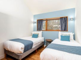 A bedroom with two single beds a small round wooden table and a window with blue curtains at Cropton Silver Birch Compact in Cropton Forest
