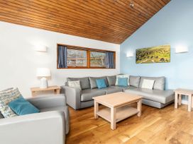 A living room with grey sofas cushions wooden tables and a wooden ceiling at Cropton Silver Birch Compact in Cropton Forest
