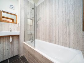 A bathroom with a bathtub shower combination and a sink with mirror at Cropton Silver Birch Compact in Cropton Forest