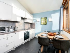 A kitchen and dining area with white cabinets a wooden table set with plates and glasses and a large window at Cropton Silver Birch Compact in Cropton Forest