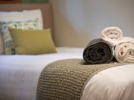 A bedroom with a bed with rolled towels placed on a textured runner at Strathyre Golden Oak Lochside Strathyre Ben Ledi