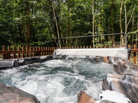 A bubbling hot tub on a wooden deck surrounded by trees at Glentress Forest Silver Birch in Glentress Forest Peebles