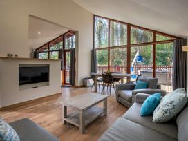 A living area with sofas and a coffee table next to large windows and a dining table at Cropton Silver Birch wheelchair accessible cabin in Cropton Forest