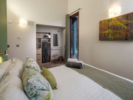 A bedroom with a bed pillows and towels a wardrobe with robes a small stool and a window with curtains at Garwnant Golden Oak Valley View in Garwnant Bannau Brycheiniog Brecon Beacons