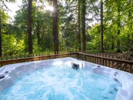 A bubbling hot tub on a wooden deck surrounded by trees at Glentress Forest Golden Oak Treehouse Glentress Forest Peebles